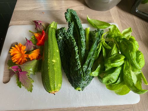 My chopping board featuring the bright oranges and purples of calendula and tree spinach. Along with the greens of courgette, kale, and basil.