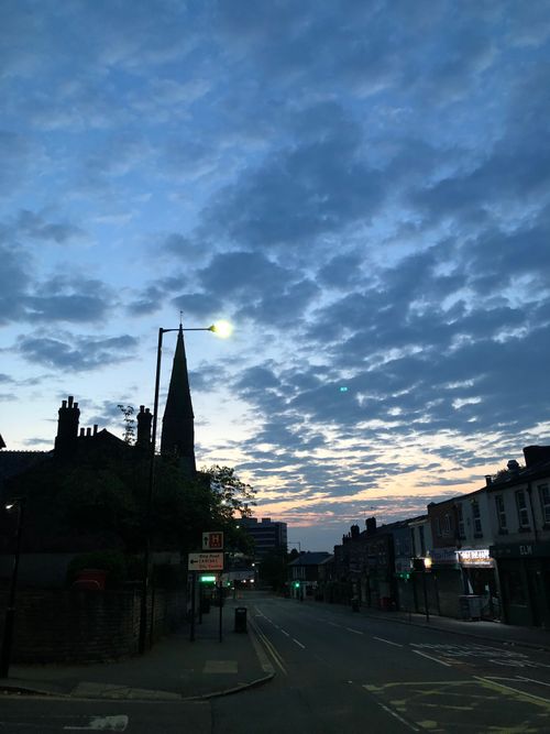 City street, dawn. The sun begins to rise as street lights remain bright.