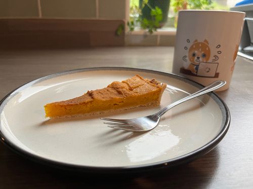 A little portion of pumpkin pie on a plate. This is my breakfast portion, there's a mug of coffee too, with Nikkei's denshiba and the FT's Origami logo.